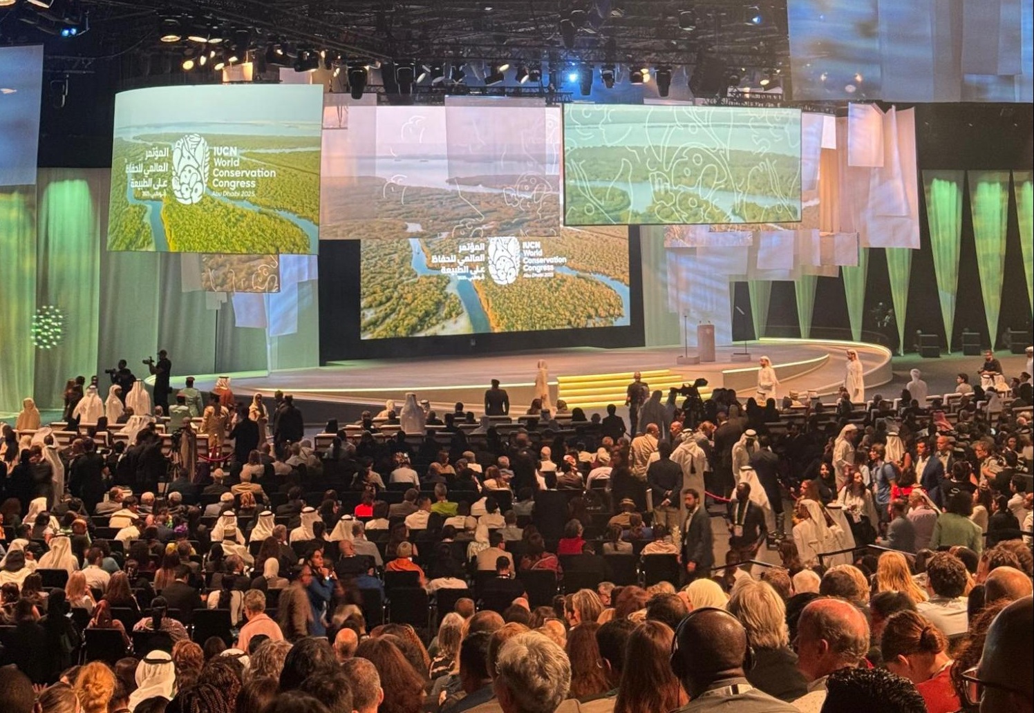 A large crowd assembled in an auditorium. On stage, various screens display Conservation Congress branding and nature imagery.